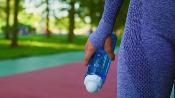 ジョギング前に女性が保有する水でいっぱいのボトルの詳細 8KでRedヘリウムカメラで撮影する — ストック動画