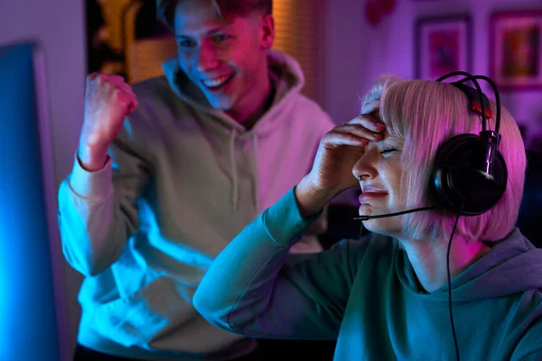 白人妇女晚上在台式电脑上玩游戏 她的朋友支持她 — 图库照片
