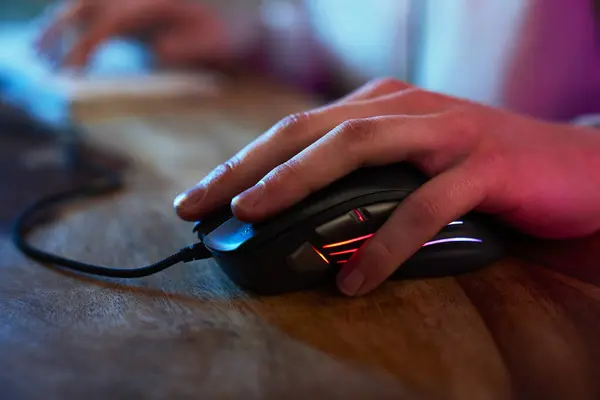 Detail of computer mouse used by gamer at night