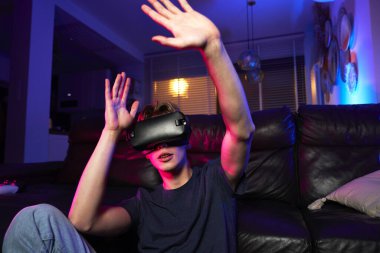 Kafkasyalı genç adam VR gözlüğü kullanırken eğleniyor.