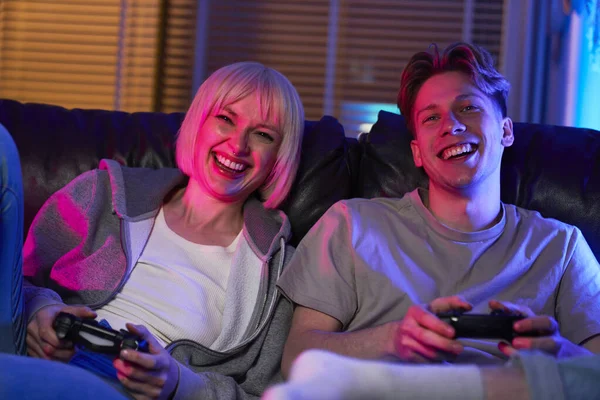 Caucasian couple playing video game with game pads and having fun