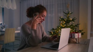 Genç beyaz kadın internet üzerinden alışveriş yapıyor cep telefonu ve dijital dizüstü bilgisayar kullanıyor. 8K 'da kırmızı helyum kamerayla çekildi..  