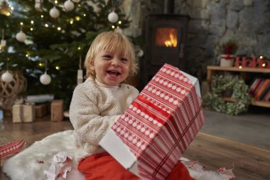 Neşeli beyaz çocuk Noel hediyesini açıyor. 