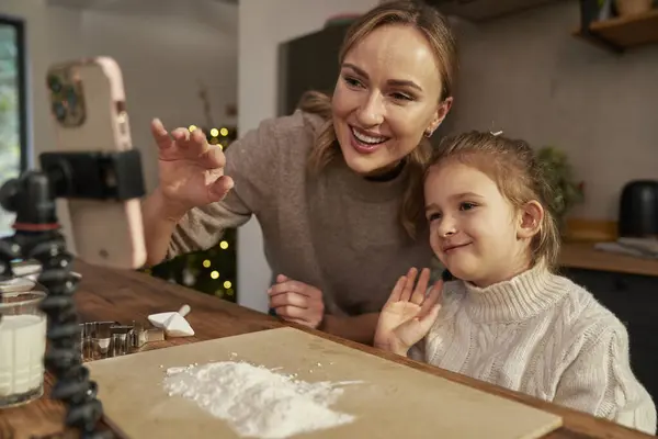 Mother and daughter having video call while Christmas baking