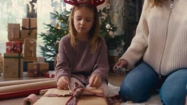 Beyaz bir kız ve anne yerde Noel hediyelerini paketliyor. 8K 'da kırmızı helyum kamerayla çekildi.. 