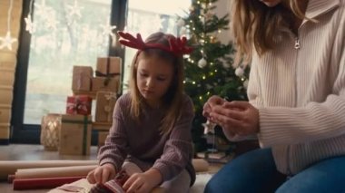Beyaz bir kız ve anne yerde Noel hediyelerini paketliyor. 8K 'da kırmızı helyum kamerayla çekildi..    