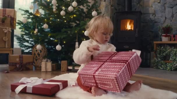 Белый Малыш Распаковывает Рождественский Подарок Съемка Красной Гелиевой Камерой — стоковое видео