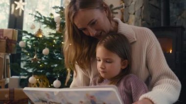 Anne ve kızı Noel zamanı kitap okuyorlar. 8K 'da kırmızı helyum kamerayla çekildi..   