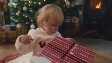 Beyaz çocuk, Noel hediyesini açıyor. 8K 'da kırmızı helyum kamerayla çekildi..   