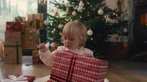Белый Малыш Распаковывает Рождественский Подарок Съемка Красной Гелиевой Камерой — стоковое видео