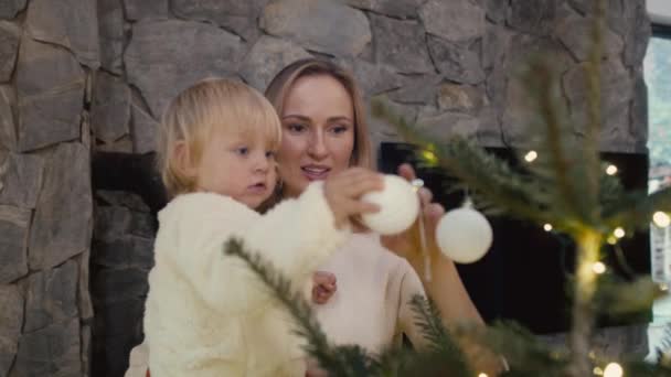 Anya Egy Kisbabát Cipel Karácsonyfa Mellett Áll Lövés Red Hélium — Stock videók