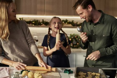 Üç kişilik beyaz bir aile ev mutfağında zencefilli ekmek yapıyor.