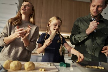 Üç kişilik beyaz bir aile ev mutfağında zencefilli ekmek yapıyor.