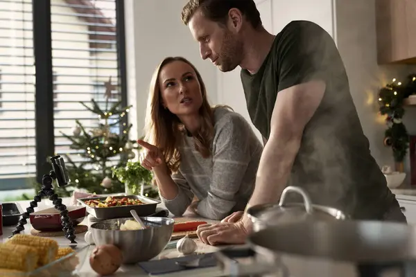 Caucasian couple preparing food before Christmas and using mobile phone