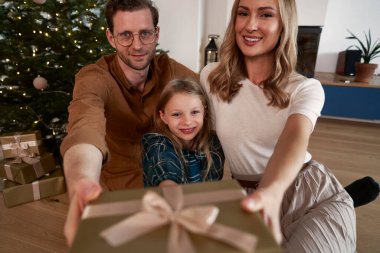 Beyaz bir aile kameraya Noel hediyesi veriyor.