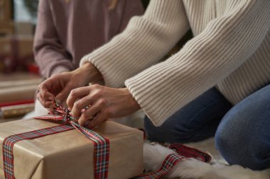 Tanınmayan kız ve annenin elleri Noel hediyelerini yere yapıştırıyor.