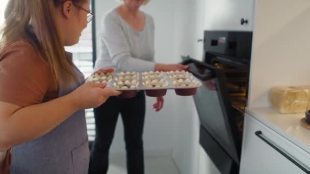 ダウン症の女性と母親は生のカップケーキをオーブンに入れました 8KでRedヘリウムカメラで撮影する — ストック動画