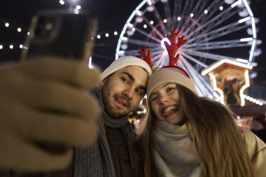 Genç çift gece Noel pazarında selfie çekiyor.