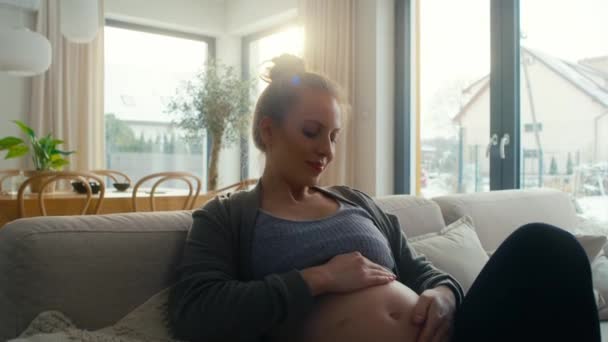 ソファーに座って腹部に触れる白人妊婦 — ストック動画