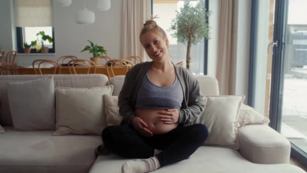 ソファーに座って腹部に触れる白人妊婦の肖像画 — ストック動画