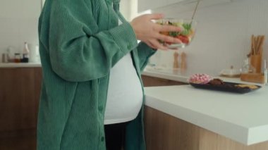 Tanımlanamayan hamile bir kadın bir kase salatadan daha tatlı atıştırmalıkları seçiyor.