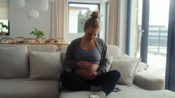 Καυκάσια Έγκυος Γυναίκα Κάθεται Στον Καναπέ Και Αγγίζει Την Κοιλιά — Αρχείο Βίντεο