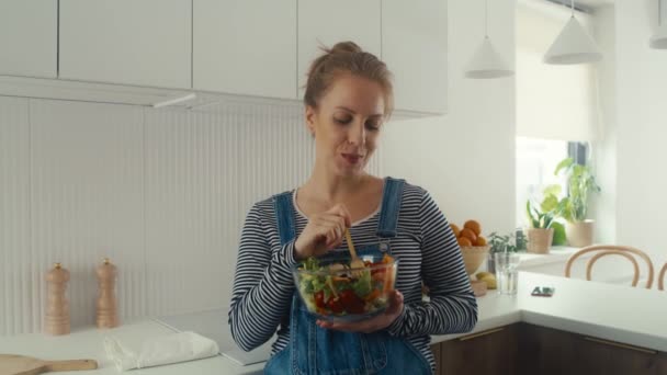 キッチンに立ってサラダのボウルを食べる白人女性 — ストック動画