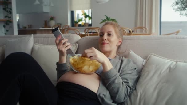 Mujer Embarazada Viendo Televisión Comiendo Patatas Fritas — Vídeo de stock