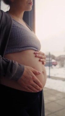 Kafkasyalı hamile bir kadının karnına dokunduğu dikey video.