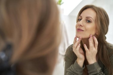 Kafkasyalı hamile kadın aynada kendine bakıyor.