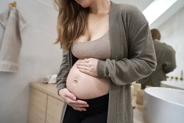白人孕妇站在浴室里摸着她的腹部 — 图库照片
