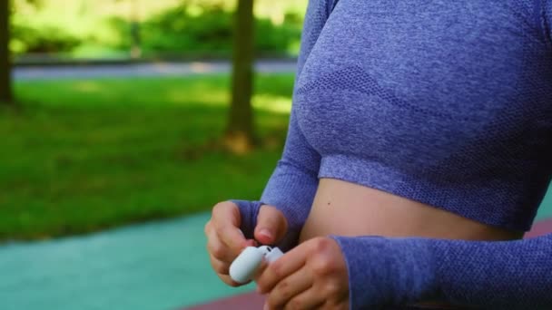 屋外で運動する前にイヤホンを適用する若い女性 — ストック動画