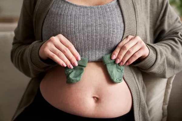 无法辨认的孕妇抱着婴儿袜在肚子上 — 图库照片