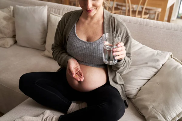 白人孕妇坐在沙发上 吃营养补充剂 — 图库照片