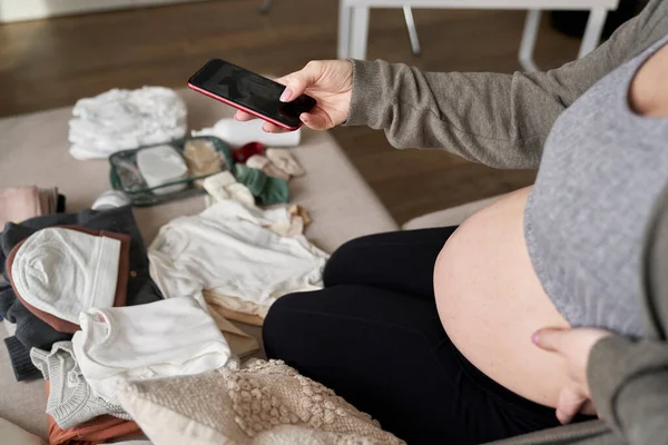 赤ちゃんの服の写真を撮る妊婦のハイアングルビュー — ストック写真