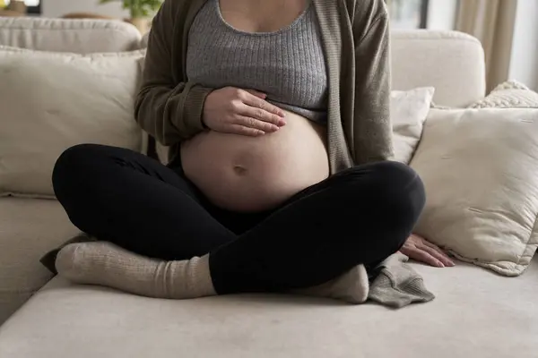 孕妇坐在沙发上摸肚子的镜头 — 图库照片