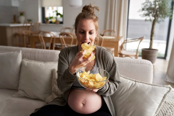 Gravid Kvinne Crisps Mens Sitter Sofa – stockfoto