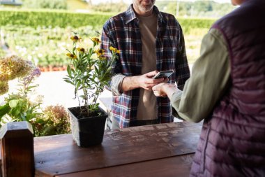 Tanımlanamayan adam ve kadın, Bahçe Merkezi 'nde temas kurmadan ödeme yapıyorlar. 