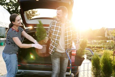 İnsanlar bahçe merkezindeki arabaya bitki paketliyor. 