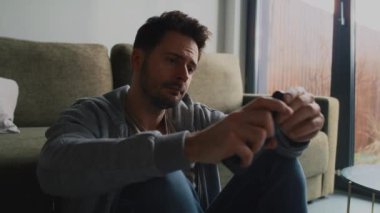 Düşünceli ve endişeli bir adam cep telefonunu kontrol ediyor.