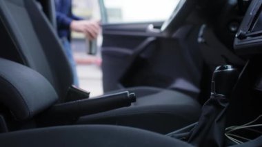 Adam arabaya biniyor ve kahve içiyor.