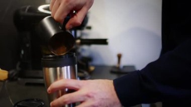 Adam seyahat bardağına ev yapımı kahve dolduruyor.