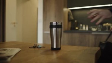 Tanınmayan adam anahtarları alıyor, seyahat kupasıyla işe gidiyor.