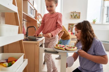 Anaokulunda birlikte oynayan iki kız çocuğu.