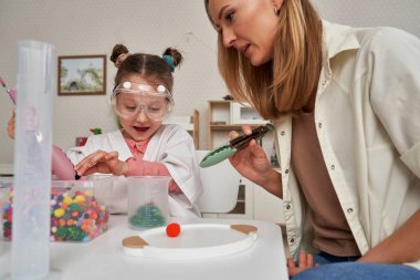 Child in lab coat having sensory exercises with a teacher clipart