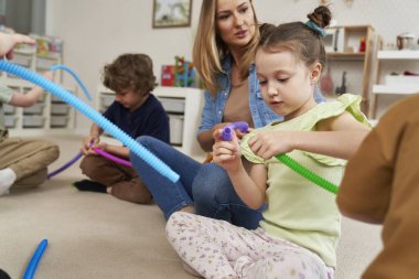 Öğretmen ve çocuklar borularla duyusal egzersizler yapıyorlar.