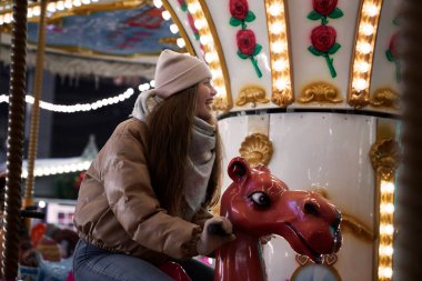 Genç beyaz kadın atlıkarıncada eğleniyor.
