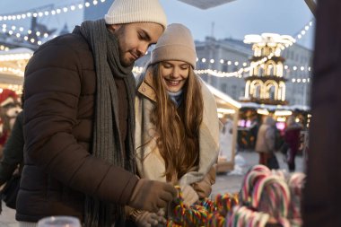 Kafkasyalı çift geceleri Noel pazarından şeker alıyor.