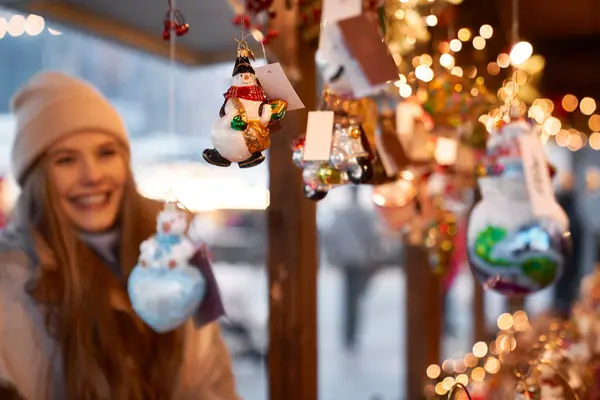 クリスマスマーケットでクリスマスの装飾を見ている白人女性 — ストック写真