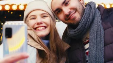 Genç çift gece Noel pazarında selfie çekiyor.